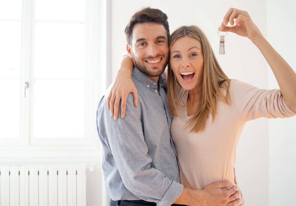 Happy couple holding keys to new home.